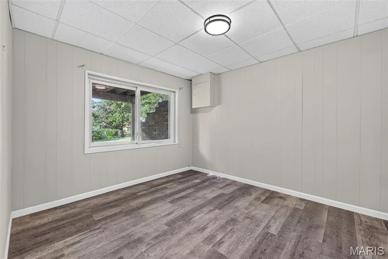 Bright, versatile room featuring wood-finish plank flooring, white vertical shiplap walls, and a recessed ceiling fixture — 1319 Brandywine Lane, St Peters, MO 63376