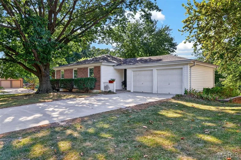 Brick and siding exterior with a two-car garage, concrete driveway, and mature landscaping — 1319 Brandywine Lane, St Peters, MO 63376