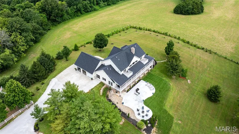 Expansive exterior featuring a large concrete patio, surrounding green lawn, and a multi-level deck with white railings — 205 Howell Road, Defiance, MO 63341