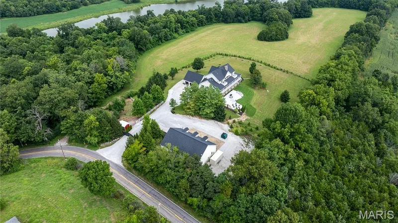Expansive estate with a main residence and an additional structure, surrounded by mature trees and verdant fields — 205 Howell Road, Defiance, MO 63341