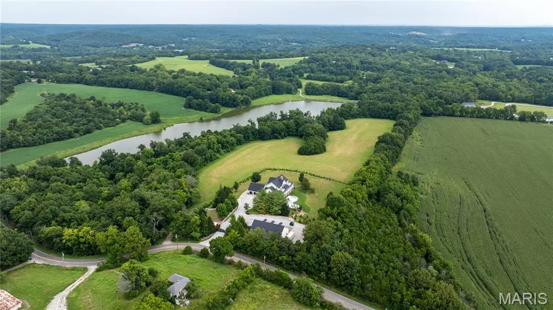 Expansive property featuring a large body of water, extensive green fields, and mature tree lines — 205 Howell Road, Defiance, MO 63341