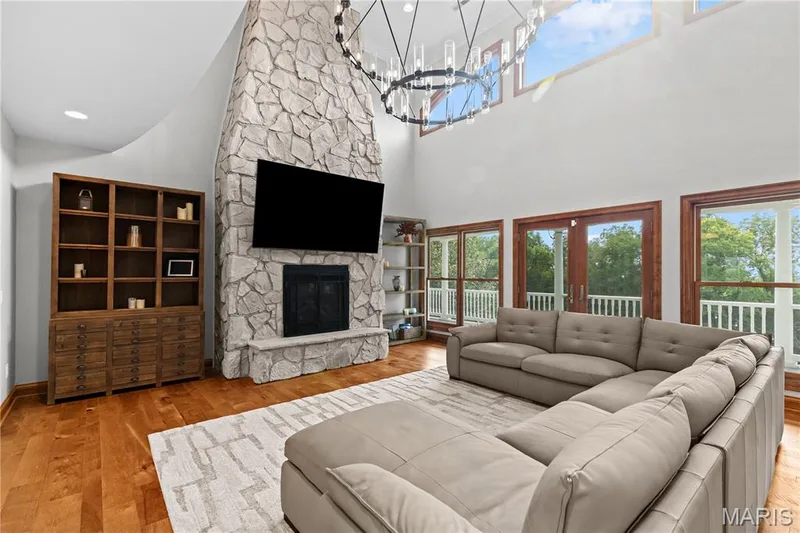 Two-story stone fireplace, wood-finish flooring, and a large chandelier — 205 Howell Road, Defiance, MO 63341