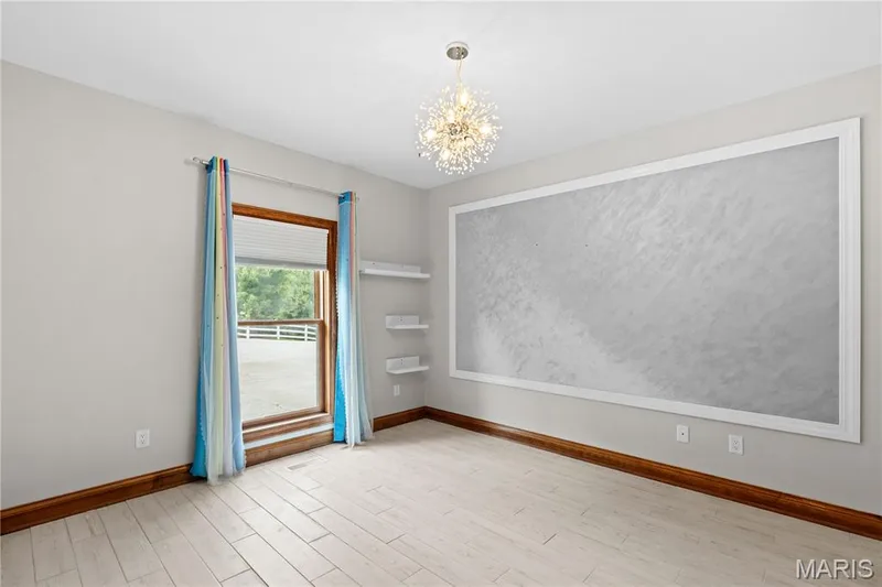 Light wood-finish flooring, a contemporary chandelier, built-in shelving, and a prominent framed accent wall — 205 Howell Road, Defiance, MO 63341