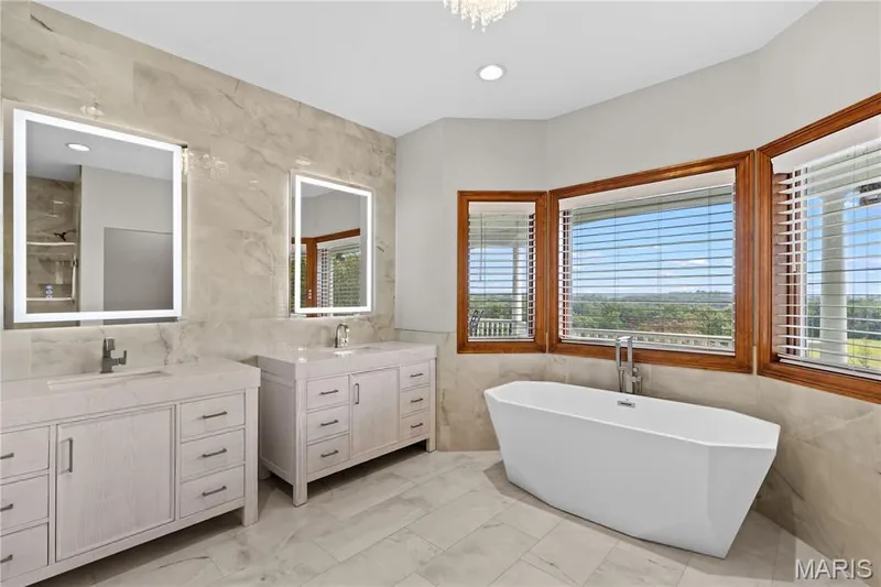 Dual vanity with integrated sinks, illuminated mirrors, and light-toned cabinetry — 205 Howell Road, Defiance, MO 63341