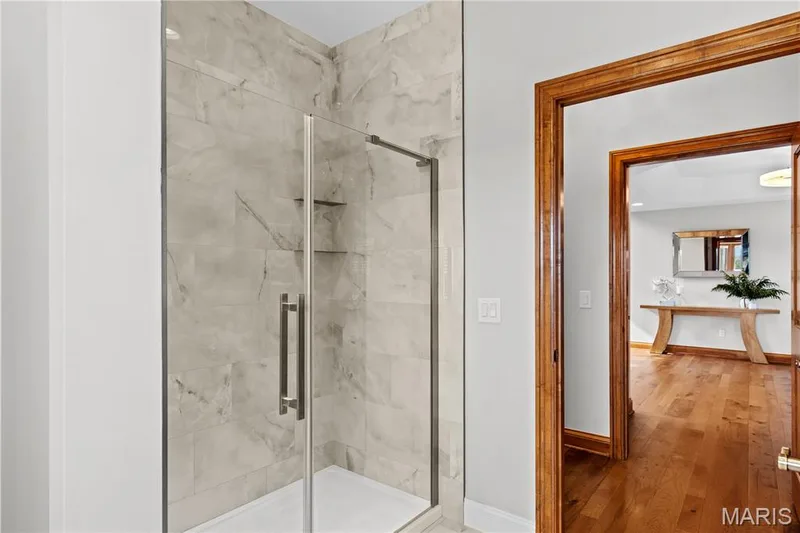 Glass-enclosed shower with full-height stone-look tile surround and integrated shelving — 205 Howell Road, Defiance, MO 63341