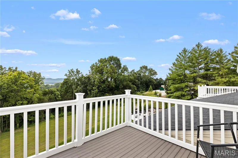 Expansive outdoor deck with composite decking, white railing, and a distant tree-lined landscape — 205 Howell Road, Defiance, MO 63341