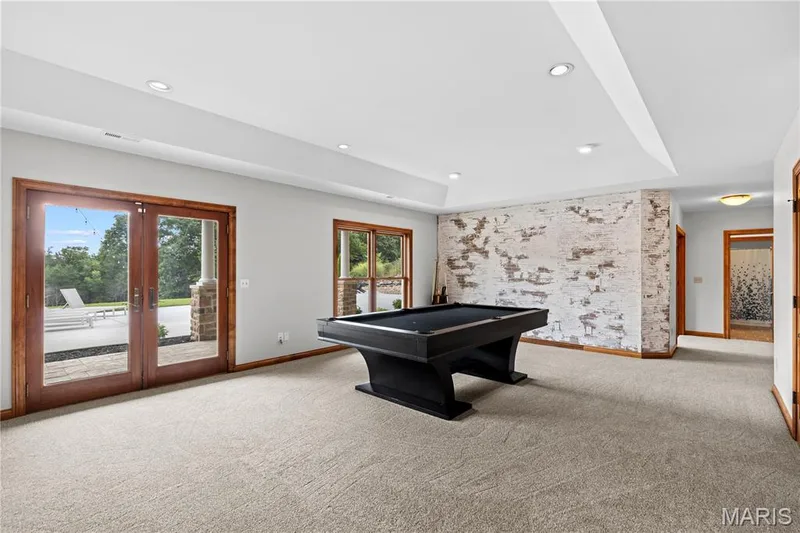 Recessed lighting illuminates a spacious room featuring a tray ceiling and light-colored carpeting — 205 Howell Road, Defiance, MO 63341