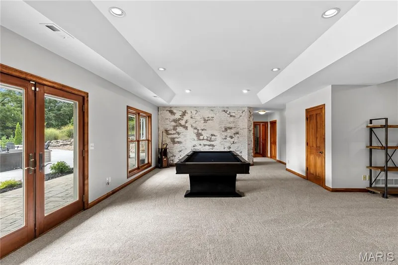 Spacious room featuring light-toned carpeting, recessed ceiling lighting, and a brick-finish accent wall — 205 Howell Road, Defiance, MO 63341