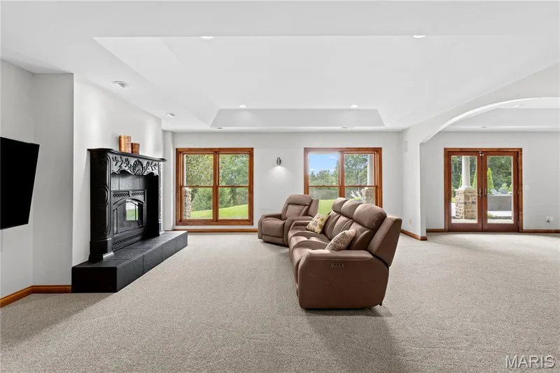 Spacious room with a decorative fireplace, large windows, and double glass doors — 205 Howell Road, Defiance, MO 63341