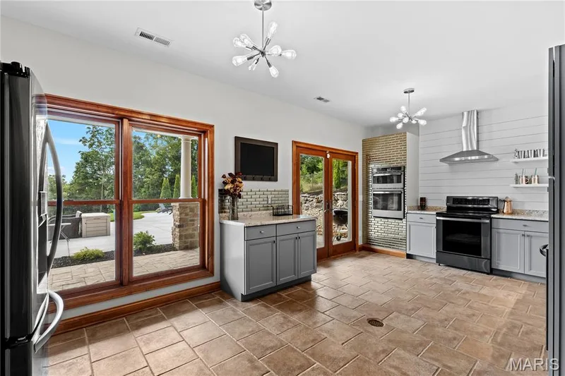 Spacious kitchen featuring gray cabinetry, stainless steel appliances, stone countertops, and tile flooring — 205 Howell Road, Defiance, MO 63341
