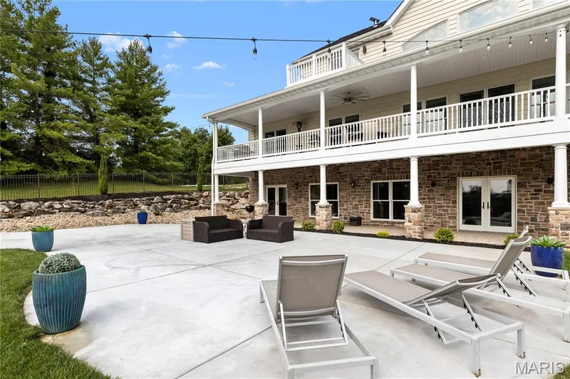 Expansive concrete patio with a retaining wall and mature trees — 205 Howell Road, Defiance, MO 63341