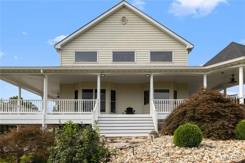 Expansive wrap-around porch with white railings and recessed lighting — 205 Howell Road, Defiance, MO 63341