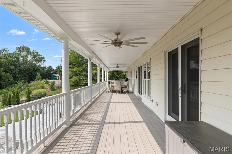 Expansive covered porch featuring a composite deck, classic white railings, and multiple ceiling fans — 205 Howell Road, Defiance, MO 63341