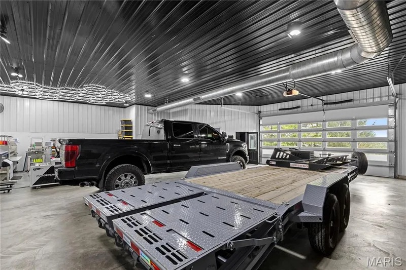 Concrete flooring, metal corrugated ceiling, recessed lighting, exposed spiral ductwork, and glass-paned overhead door — 205 Howell Road, Defiance, MO 63341