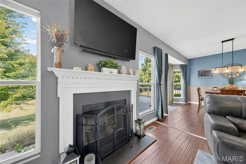 The living room offers a wood burning fireplace that is flanked by windows which spill plenty of natural light. — 1125 Crystal Creek Parkway, Wentzville, MO 63385