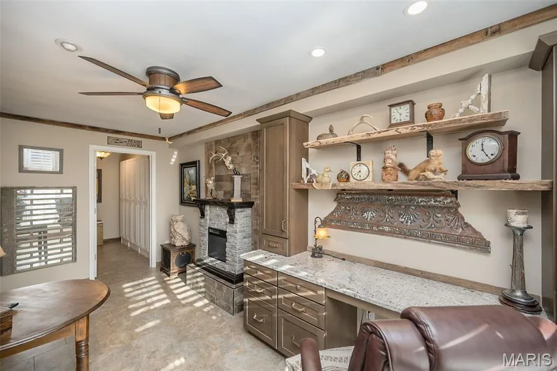 This den features an electric fireplace and built in desk and cabinets with granite desktop — 1512 Bedford Forge Court #19, Chesterfield, MO 63017