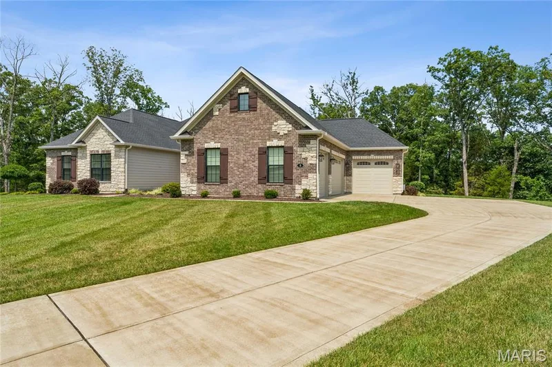 Brick and stone facade residence with a two-car garage, dark-shingle roof, and a concrete driveway — 5 Timberdel Place, Foristell, MO 63348