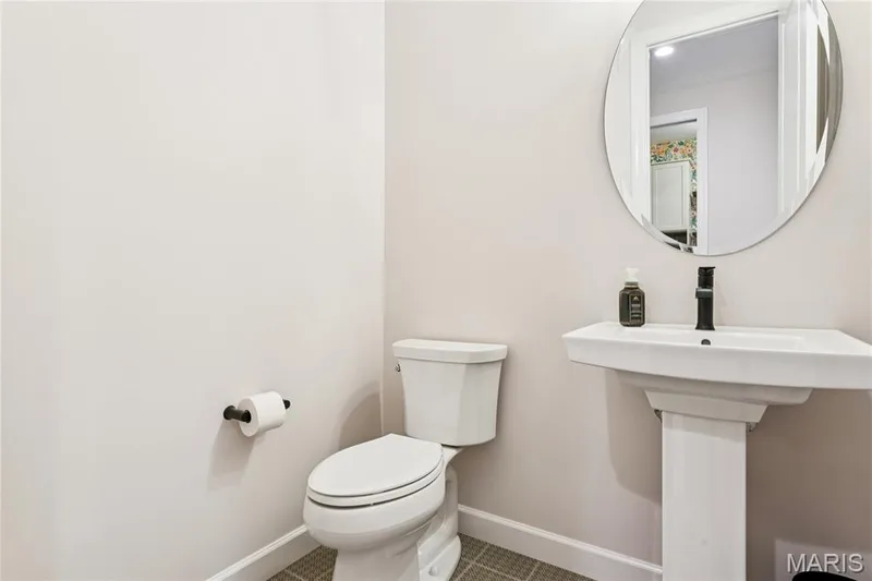 Pedestal sink with black faucet, oval wall mirror, and white toilet — 5 Timberdel Place, Foristell, MO 63348
