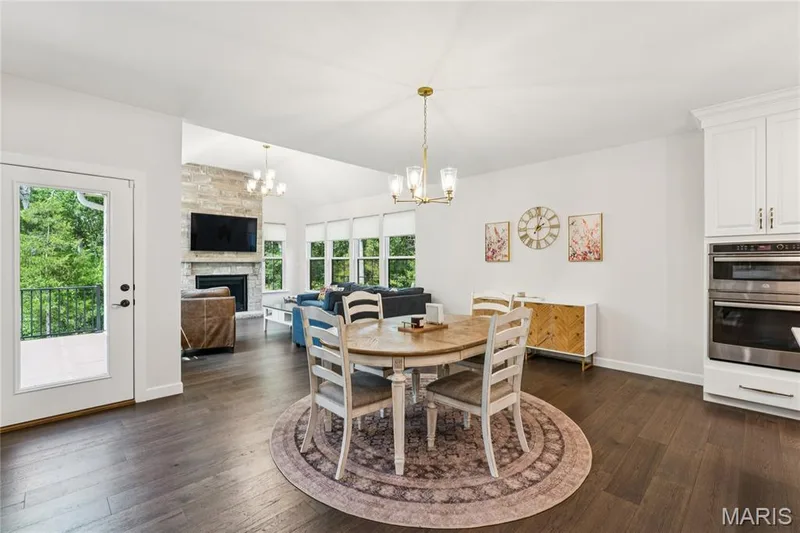Wood-finish flooring throughout, white cabinetry with built-in stainless steel double ovens, and a gold-tone chandelier — 5 Timberdel Place, Foristell, MO 63348