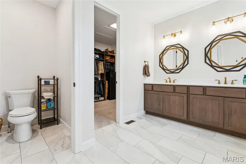 Double vanity with light countertops and wood-finish cabinetry — 5 Timberdel Place, Foristell, MO 63348