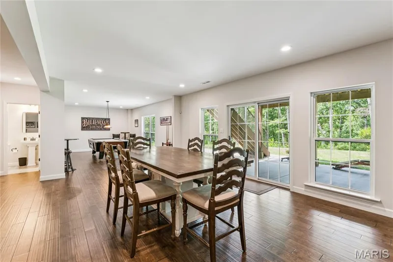 Expansive open-concept room with wood-finish flooring, recessed lighting, and a sliding glass door — 5 Timberdel Place, Foristell, MO 63348
