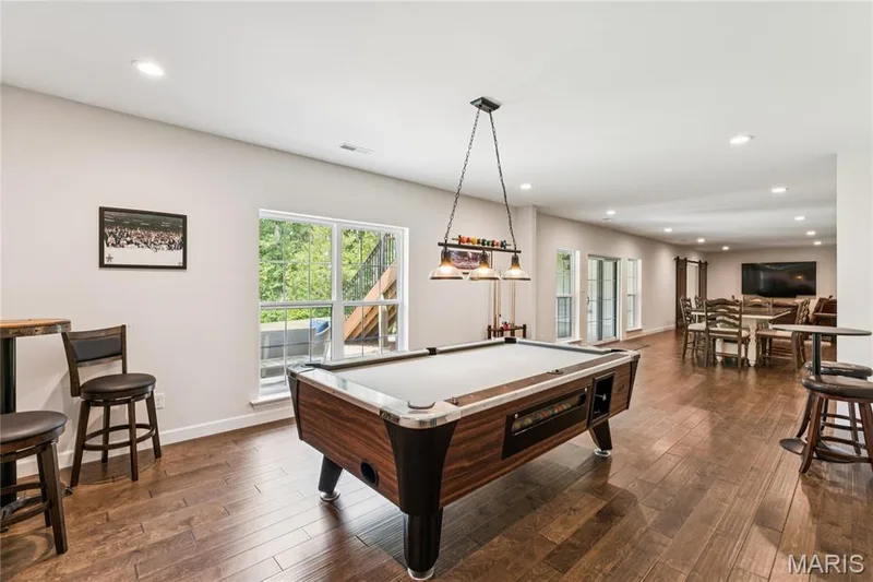 Spacious recreation area featuring wood-luxury vinyl flooring, recessed lighting, large windows, and French doors — 5 Timberdel Place, Foristell, MO 63348