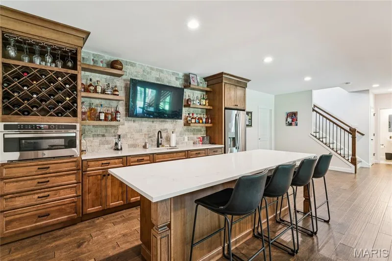 Built-in quartz countertop wet bar featuring a beverage refrigerator, integrated microwave/oven combo, and wine storage — 5 Timberdel Place, Foristell, MO 63348
