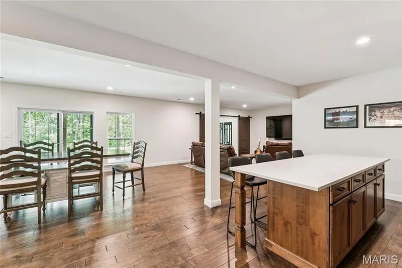 Kitchen island with a quartz countertop and wood-finish cabinetry, recessed lighting, and luxury vinyl flooring — 5 Timberdel Place, Foristell, MO 63348