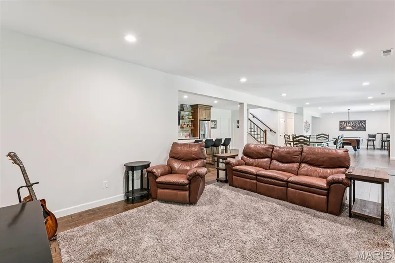 Recessed lighting illuminates the open-concept lower level with wood-finish flooring — 5 Timberdel Place, Foristell, MO 63348