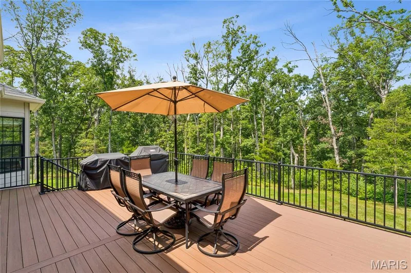 Expansive outdoor 16 x 24 deck with composite decking, black metal railings, and natural surroundings — 5 Timberdel Place, Foristell, MO 63348