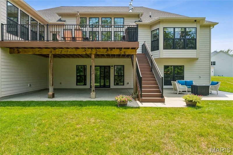 Two-story exterior with an upper-level deck, lower-level patio, and bay windows — 5 Timberdel Place, Foristell, MO 63348