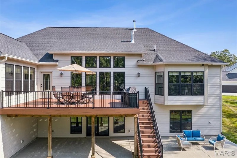 Expansive rear deck with dark railing and stairs to a lower patio — 5 Timberdel Place, Foristell, MO 63348