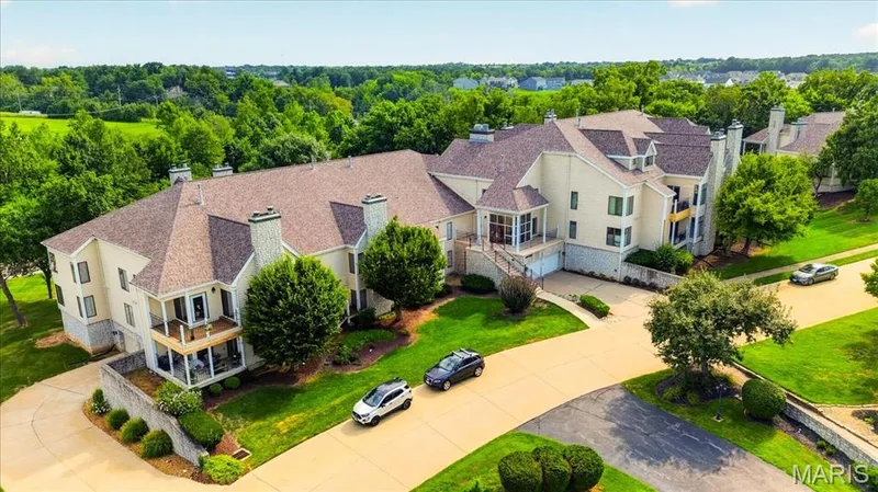 Elegant French Colonial estate showcasing a multi-level architectural design with cream-colored exterior, dormers, and professionally manicured landscaping — 1608 Lake Knoll Drive #1A, Lake St. Louis, MO 63367