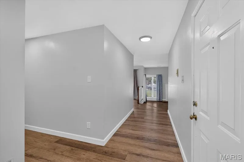 Bright hallway featuring warm wood-finish flooring, crisp white walls, and recessed ceiling lighting — 1608 Lake Knoll Drive #1A, Lake St. Louis, MO 63367