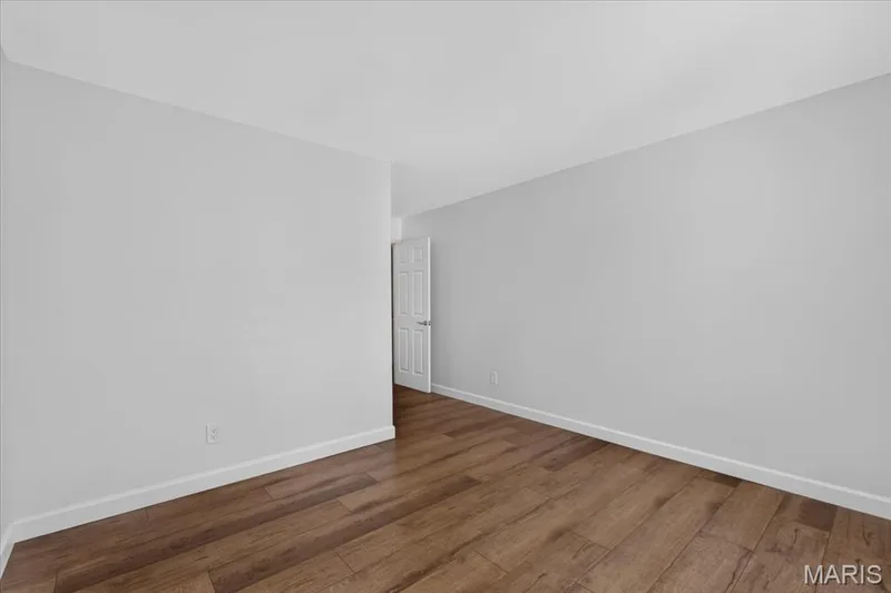 Wood-finish flooring with white trim and a paneled door — 1608 Lake Knoll Drive #1A, Lake St. Louis, MO 63367