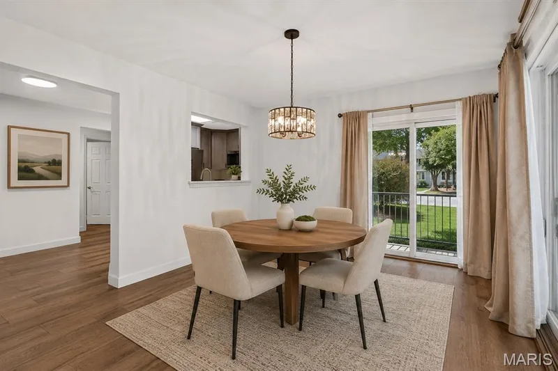 Wood-finish flooring throughout, with a decorative chandelier in the dining area. Digitally enhanced and virtually staged. — 1608 Lake Knoll Drive #1A, Lake St. Louis, MO 63367