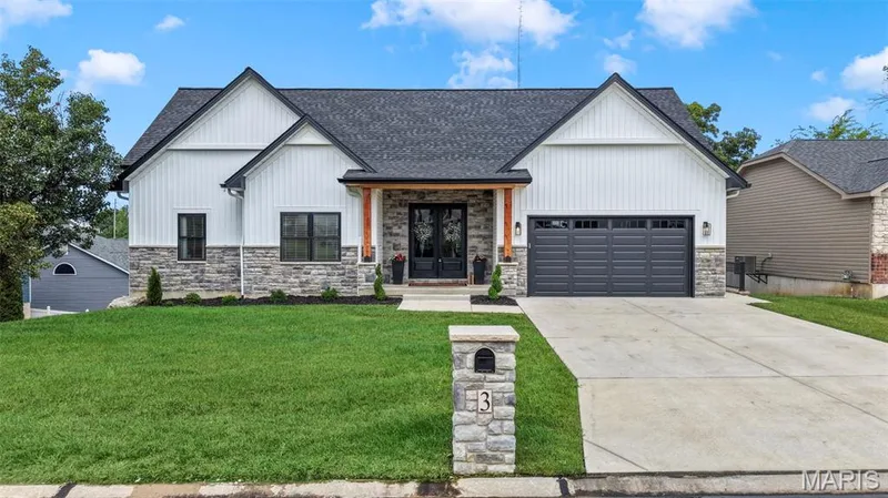 Contemporary exterior featuring white board and batten siding, stone facade accents, a dark shingle roof, a prominent front entry, and a two-car garage — 3 Millers Court, O'Fallon, MO 63366