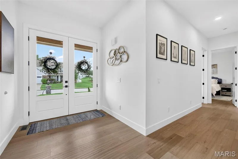 Double glass-paneled entry doors, wood-finish flooring, recessed lighting, and crisp white walls — 3 Millers Court, O'Fallon, MO 63366