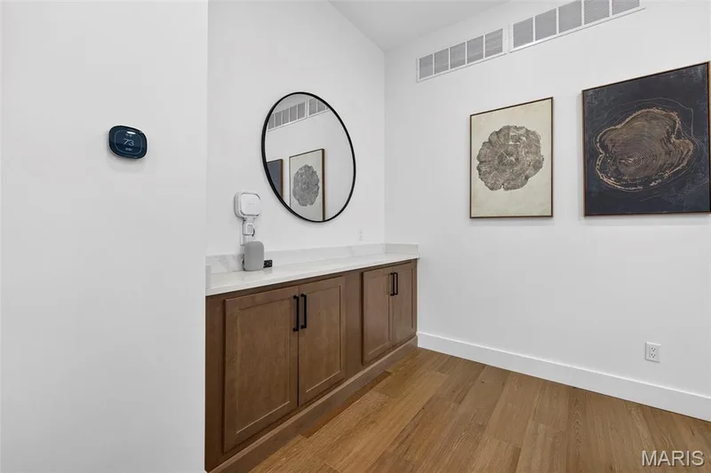 Hardwood flooring, built-in cabinetry, solid surface countertop, smart thermostat, and white walls — 3 Millers Court, O'Fallon, MO 63366