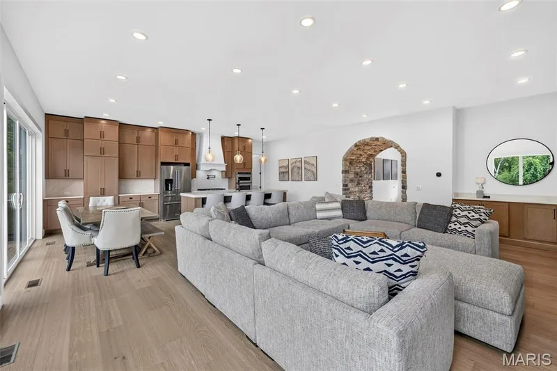 Open-concept living area with wood-finish flooring, recessed lighting, and a stone archway — 3 Millers Court, O'Fallon, MO 63366