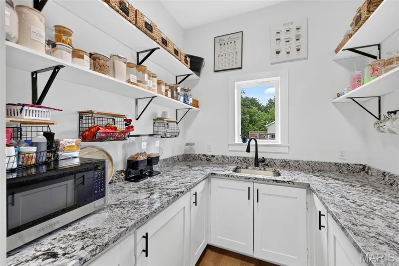 Contemporary kitchen featuring white cabinetry with matte black hardware, speckled stone countertops, and stainless steel appliances including a gas range — 3 Millers Court, O'Fallon, MO 63366