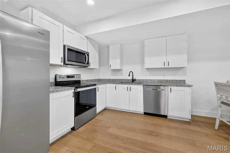 Modern kitchen featuring white cabinetry with stainless steel hardware, granite countertops, and a full suite of stainless steel appliances including a refrigerator, range, microwave, and dishwasher — 3 Millers Court, O'Fallon, MO 63366