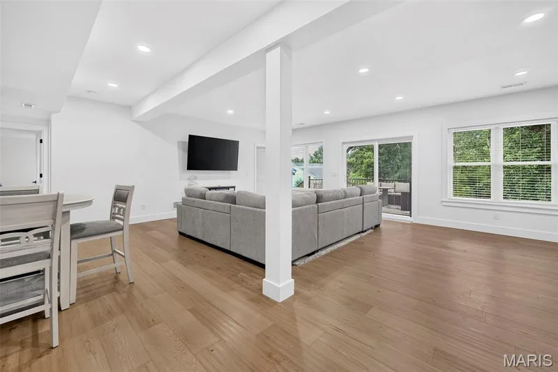Spacious living area featuring wood-finish flooring, recessed lighting, expansive windows, and a sliding glass door — 3 Millers Court, O'Fallon, MO 63366