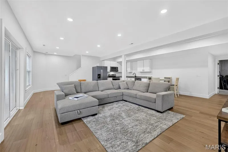 Expansive open-concept living area featuring a sectional layout with hardwood flooring throughout, recessed ceiling lighting, and seamless integration with the kitchen zone — 3 Millers Court, O'Fallon, MO 63366