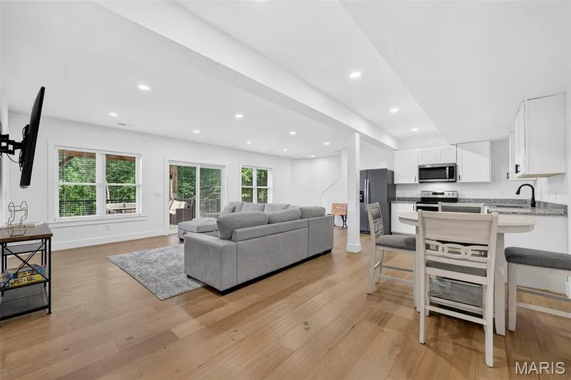 Open-concept living space featuring hardwood flooring throughout, recessed ceiling lighting, and abundant natural light from multiple large windows — 3 Millers Court, O'Fallon, MO 63366