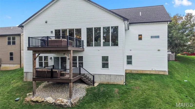 Multi-level decking with dark wood-finish railing, a ground-level patio, and a sloped grassy yard — 3 Millers Court, O'Fallon, MO 63366