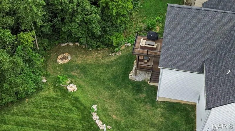 Expansive backyard oasis featuring mature tree-lined landscaping, manicured lawn, and established stone hardscaping — 3 Millers Court, O'Fallon, MO 63366