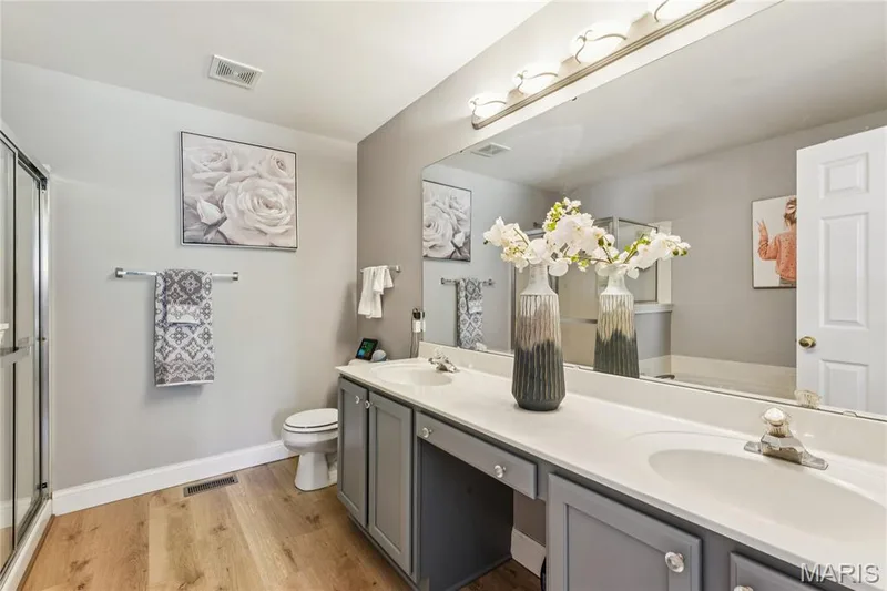 The private primary bath offers a spacious vanity with dual sinks, generous counter space, and a separate shower—an ideal complement to the main-floor suite. — 947 Rolling Thunder Drive, O'Fallon, MO 63368