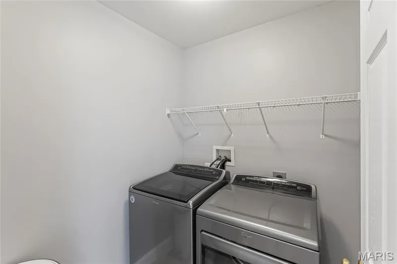 A dedicated main-level laundry room keeps everyday routines convenient, with full-size washer and dryer hookups plus additional shelving for storage and organization. — 947 Rolling Thunder Drive, O'Fallon, MO 63368