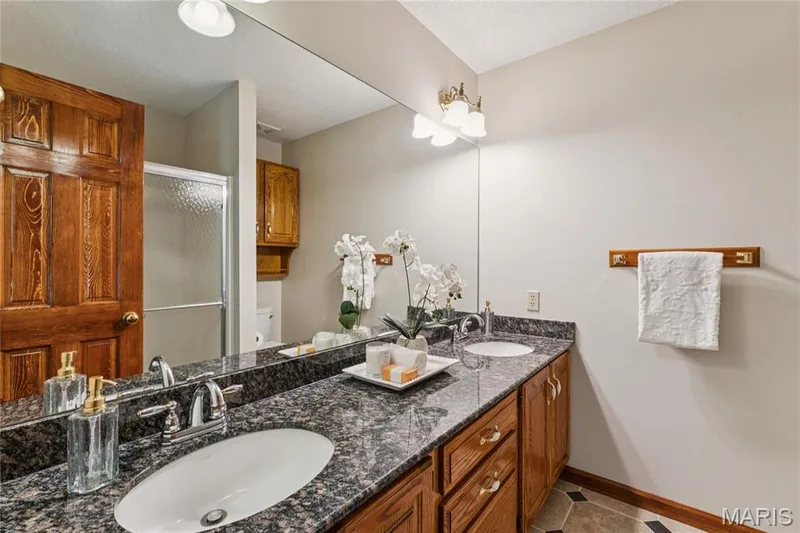 Double vanity, one expansive mirror, and a step-in glass shower, this bathroom was built for real mornings without the wait. — 416 Loiselaine Drive, O'Fallon, MO 63366